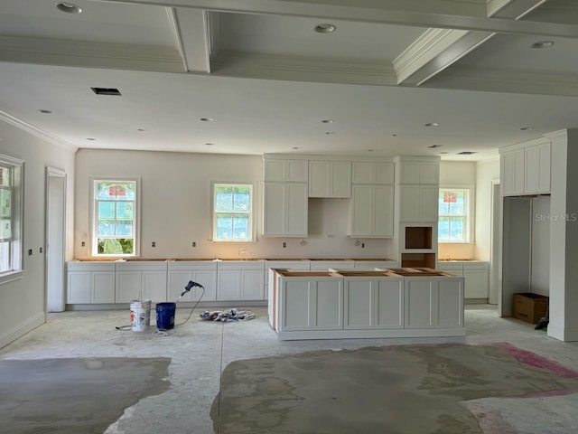 kitchen featuring white cabinets, beam ceiling, a center island, and crown molding