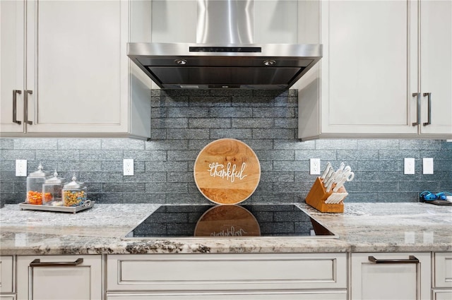 kitchen with decorative backsplash, light stone counters, and wall chimney range hood