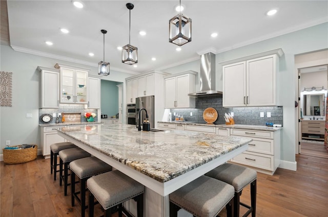 kitchen featuring white cabinets, dark hardwood / wood-style flooring, a spacious island, and wall chimney range hood