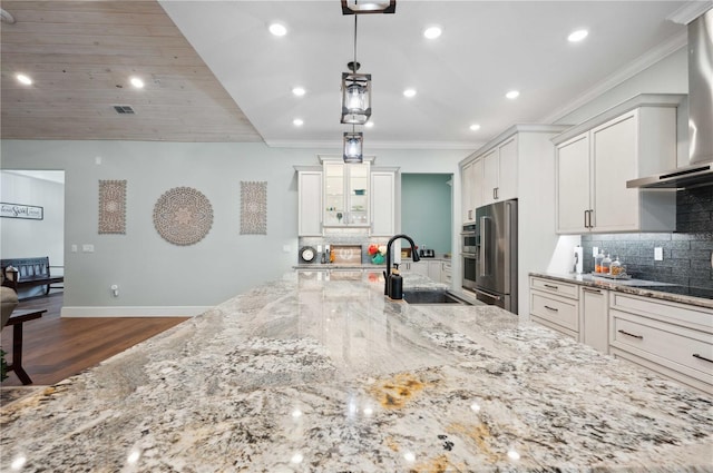 kitchen featuring sink, hanging light fixtures, wall chimney exhaust hood, light stone countertops, and high quality fridge