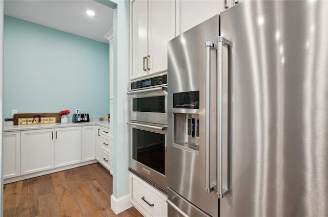 kitchen with white cabinets, stainless steel appliances, and wood-type flooring