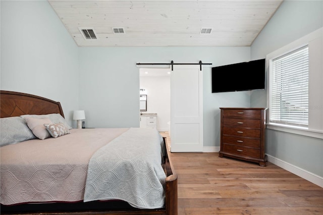 bedroom featuring light wood-type flooring, ensuite bathroom, wood ceiling, a barn door, and lofted ceiling