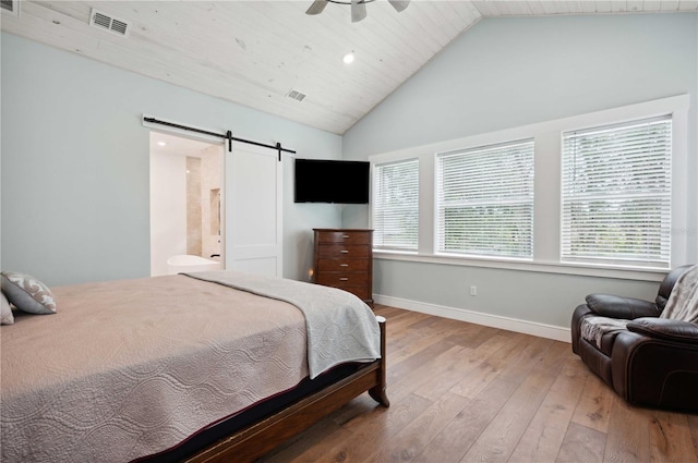 bedroom with a barn door, ceiling fan, multiple windows, and hardwood / wood-style flooring