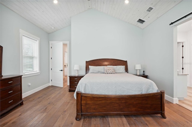 bedroom featuring light wood-type flooring, a barn door, vaulted ceiling, and wood ceiling