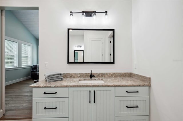 bathroom featuring lofted ceiling, wood-type flooring, and vanity