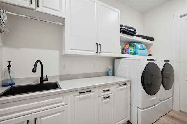 laundry area featuring light wood-type flooring, washing machine and dryer, cabinets, and sink