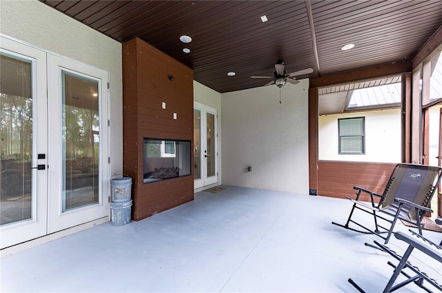 unfurnished sunroom featuring ceiling fan, wood ceiling, and french doors