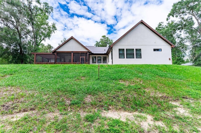 rear view of house featuring a sunroom and a lawn