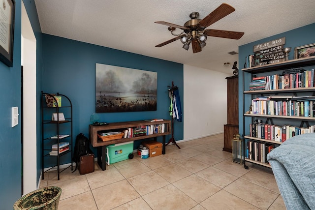 living area featuring a textured ceiling, light tile patterned floors, and ceiling fan