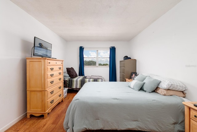 bedroom featuring a textured ceiling and light hardwood / wood-style flooring