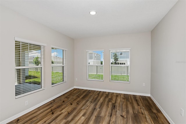 empty room with plenty of natural light and dark hardwood / wood-style flooring