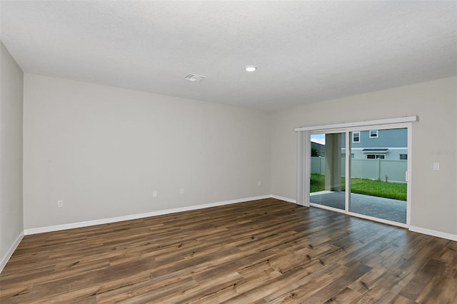 unfurnished room featuring dark wood-type flooring and a textured ceiling