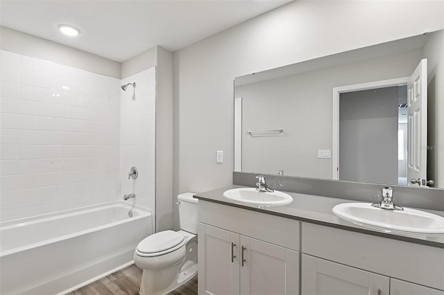 full bathroom with tiled shower / bath, toilet, wood-type flooring, and vanity