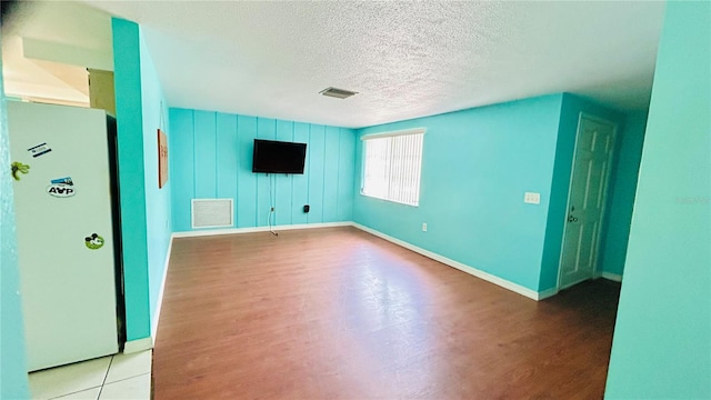 unfurnished living room featuring a textured ceiling and light hardwood / wood-style flooring