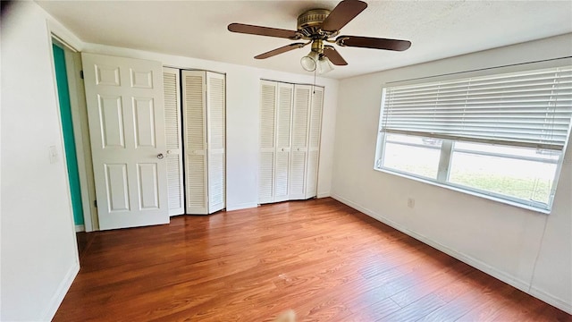 unfurnished bedroom featuring light hardwood / wood-style floors, two closets, and ceiling fan