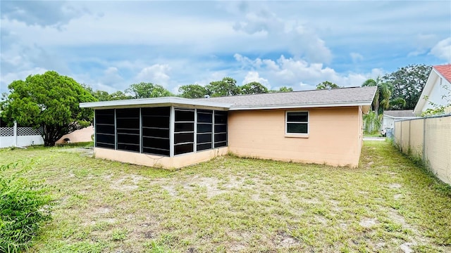 rear view of house with a sunroom and a yard