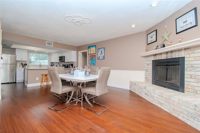 dining space with sink, hardwood / wood-style floors, and a fireplace