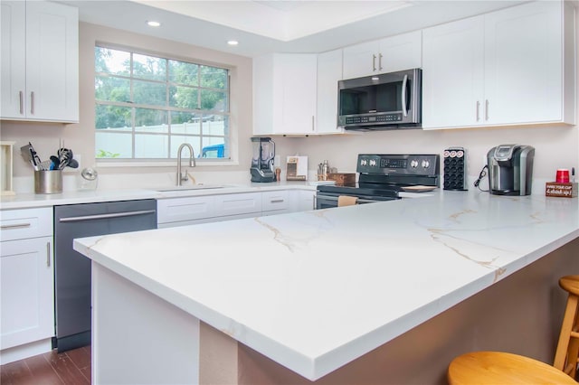 kitchen with a kitchen bar, stainless steel appliances, dark hardwood / wood-style flooring, sink, and white cabinets