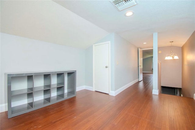 additional living space featuring lofted ceiling, hardwood / wood-style floors, and a chandelier