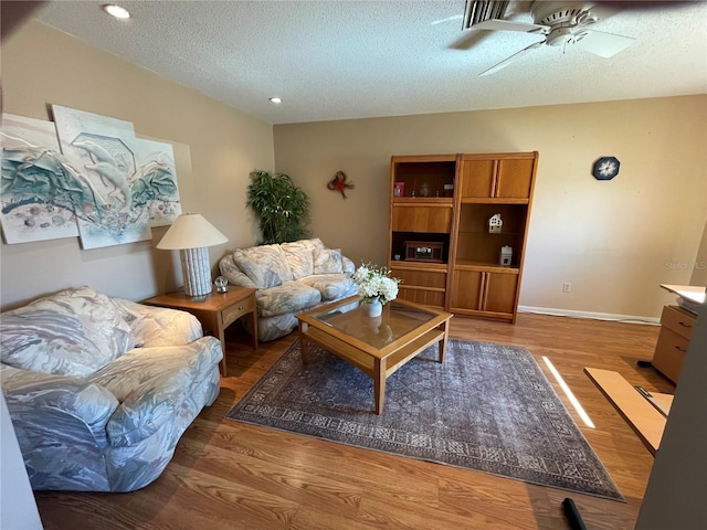 living room with recessed lighting, a ceiling fan, a textured ceiling, wood finished floors, and baseboards