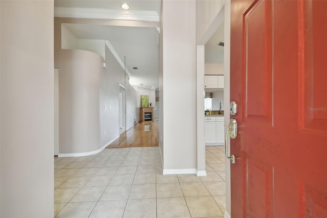 entrance foyer with sink, light tile patterned floors, and ornamental molding