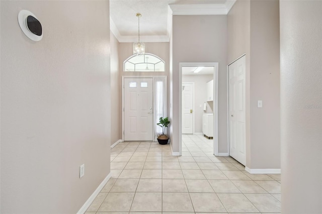 tiled foyer entrance with crown molding, a high ceiling, and a chandelier