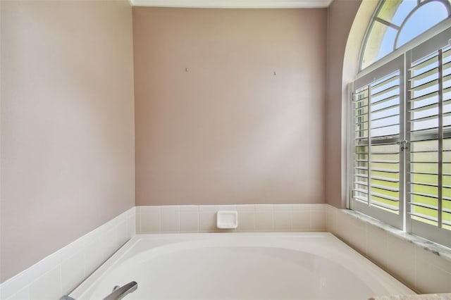 bathroom with a healthy amount of sunlight and tiled bath