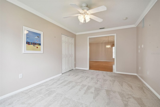 unfurnished bedroom featuring light carpet, ceiling fan with notable chandelier, and crown molding