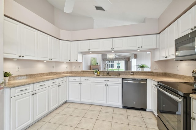 kitchen with white cabinetry, sink, a towering ceiling, light tile patterned flooring, and appliances with stainless steel finishes