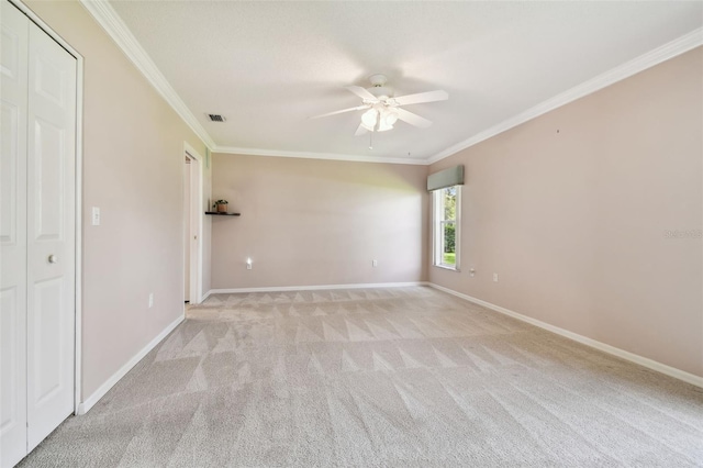 unfurnished bedroom featuring a closet, ceiling fan, crown molding, and light colored carpet