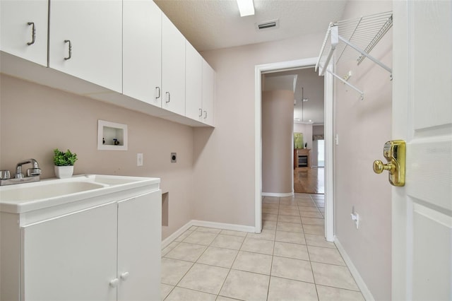 laundry area with cabinets, electric dryer hookup, hookup for a washing machine, a textured ceiling, and light tile patterned flooring