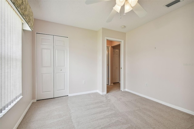 unfurnished bedroom with ceiling fan, a closet, and light carpet