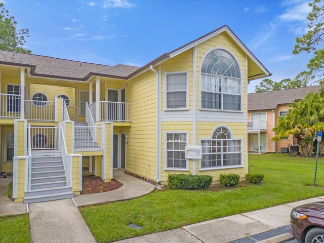 exterior space featuring central AC unit, a balcony, and a front yard