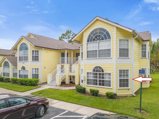 view of property with stairs and uncovered parking