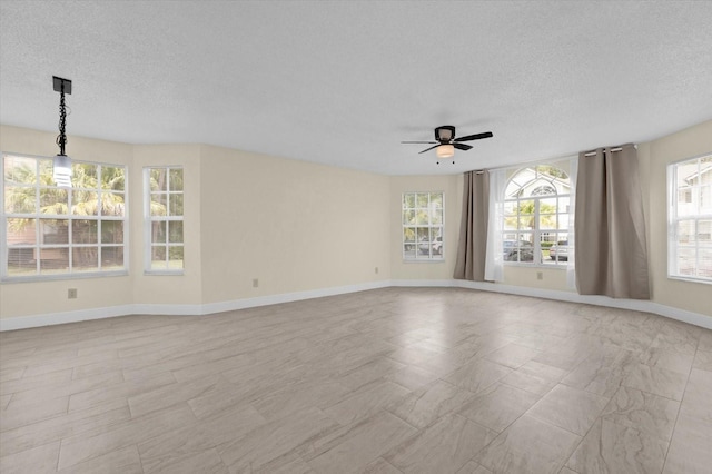 spare room with baseboards, a textured ceiling, and a ceiling fan