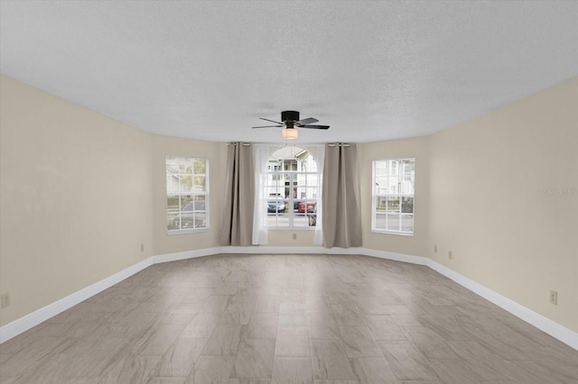 empty room with a textured ceiling, baseboards, and a ceiling fan