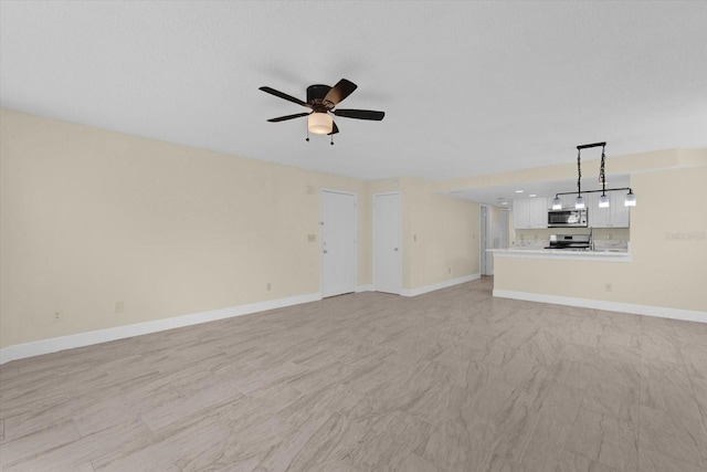 unfurnished living room featuring ceiling fan and baseboards