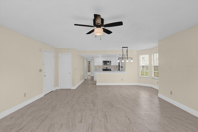 unfurnished living room with baseboards and a ceiling fan