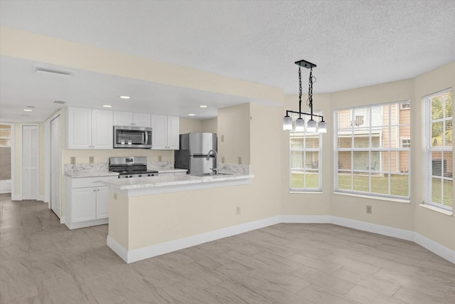 kitchen with baseboards, pendant lighting, appliances with stainless steel finishes, white cabinetry, and a sink