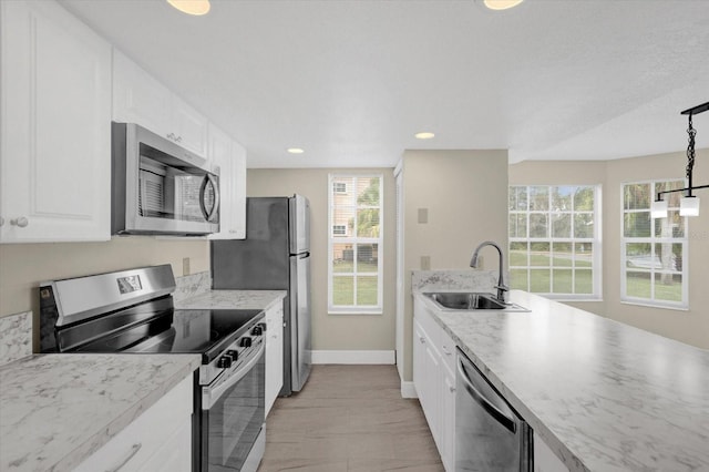 kitchen with baseboards, recessed lighting, a sink, white cabinets, and appliances with stainless steel finishes