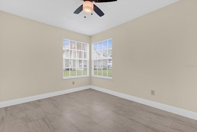 spare room featuring a textured ceiling, baseboards, and ceiling fan