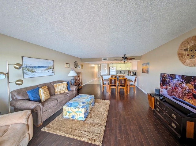 living room featuring ceiling fan, a textured ceiling, and dark hardwood / wood-style flooring