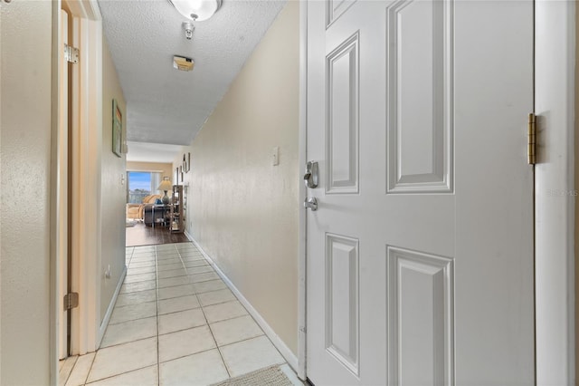 corridor featuring a textured ceiling and light tile patterned floors