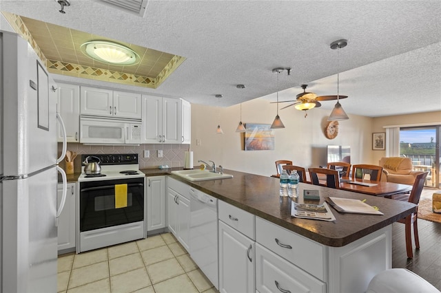 kitchen with white appliances, light wood-type flooring, kitchen peninsula, decorative light fixtures, and white cabinets