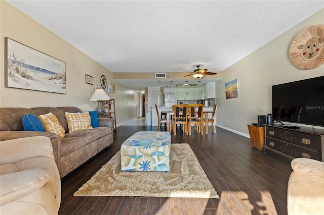 living room with a textured ceiling, dark hardwood / wood-style floors, and ceiling fan