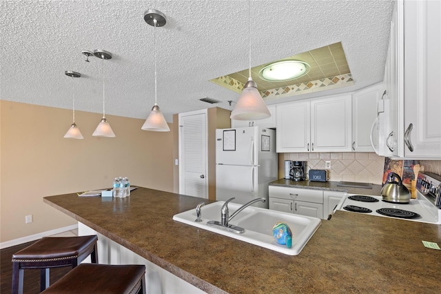 kitchen featuring a breakfast bar area, hanging light fixtures, sink, white cabinetry, and white appliances