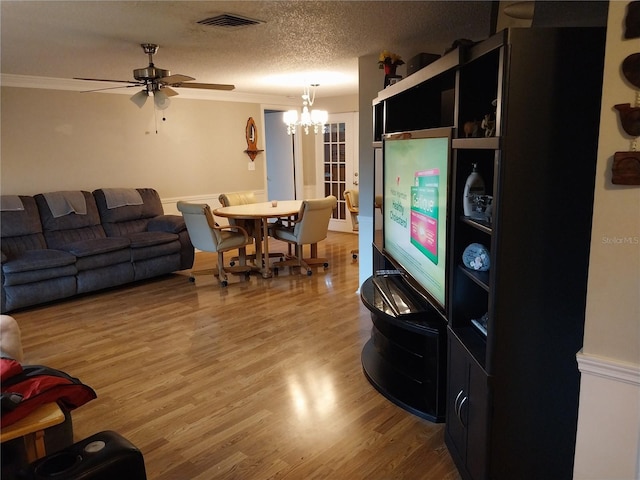 living room with ceiling fan with notable chandelier, a textured ceiling, hardwood / wood-style floors, and crown molding