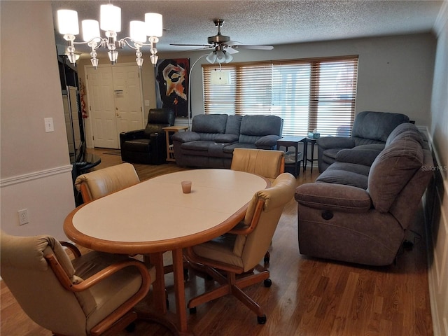 dining space featuring ceiling fan with notable chandelier, a textured ceiling, and hardwood / wood-style floors