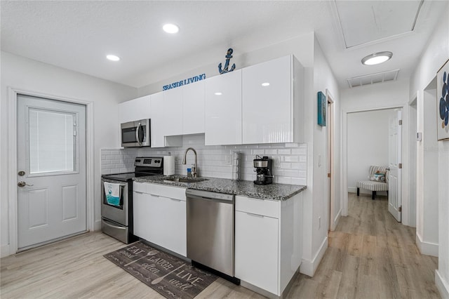 kitchen with sink, white cabinets, light hardwood / wood-style floors, and appliances with stainless steel finishes