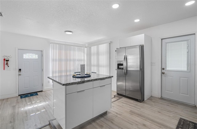 kitchen with a center island, white cabinets, light hardwood / wood-style floors, and stainless steel refrigerator with ice dispenser